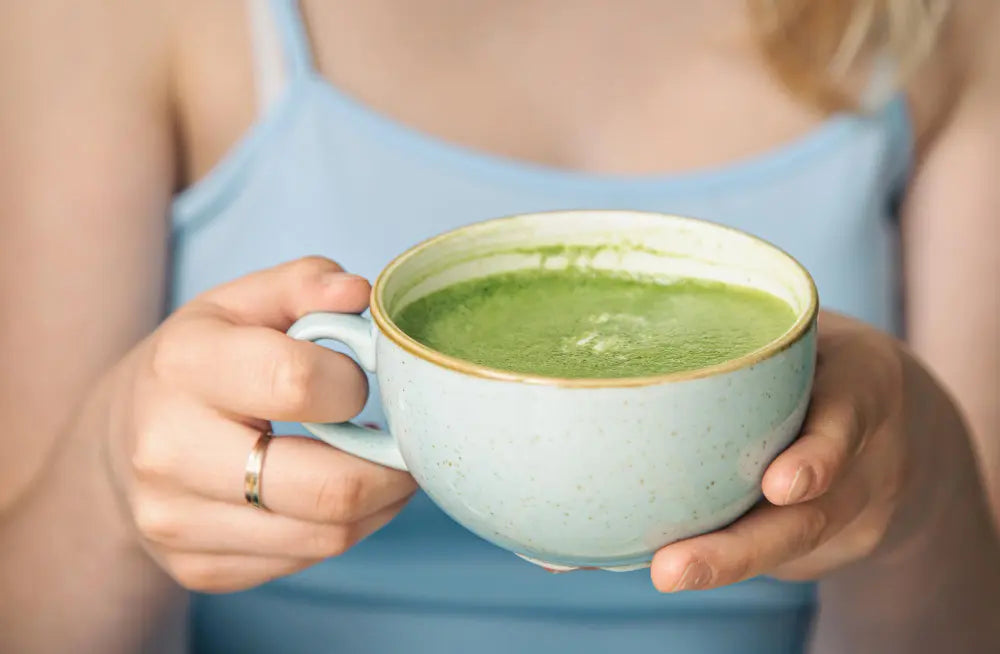 Mulher segurando xícara de superfood chá verde matcha