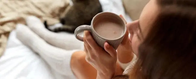 Mulher tomando chocolate quente na cama pronta para dormir
