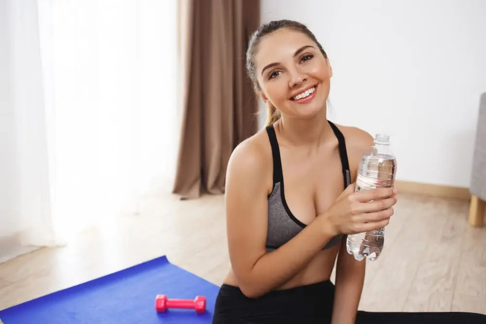 Mulher tomando água depois de se exercitar