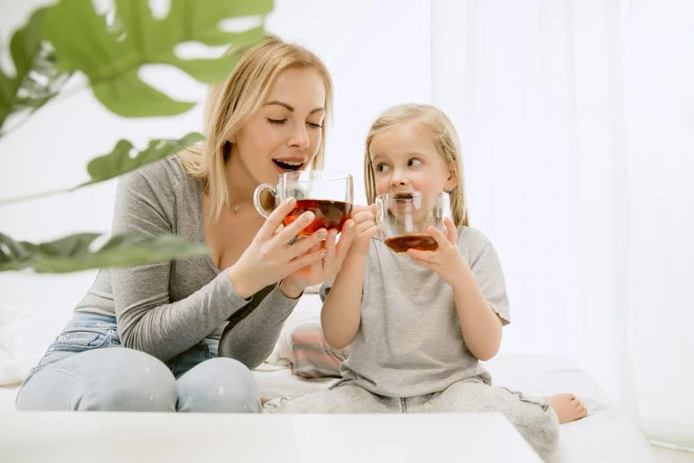 Mãe e filha segurando xícaras de chá juntas em ambiente caseiro