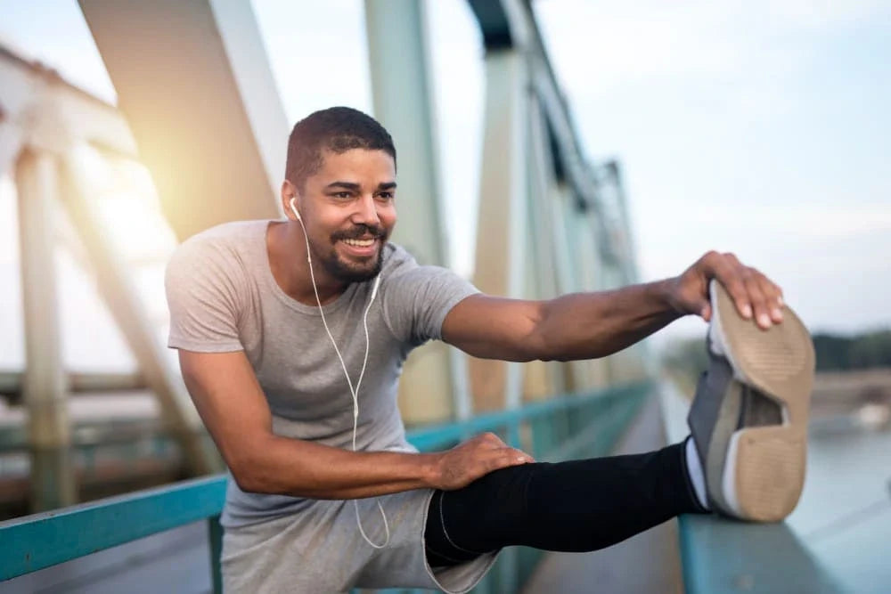 Homem usando roupas esportivas alongando a perna