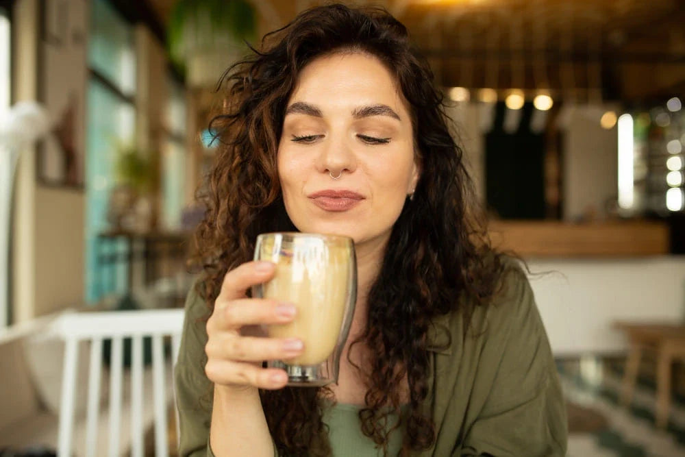 Mulher segurando copo de latte café de olhos fechados