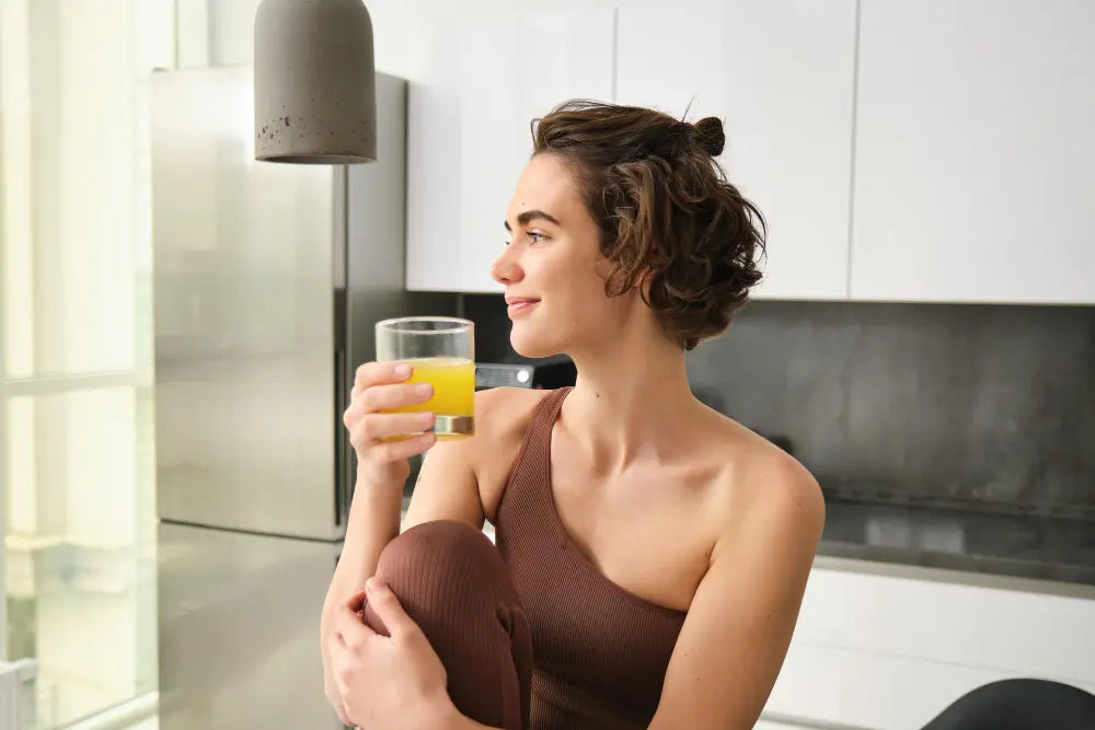Mulher tomando suco rico em antioxidantes sorrindo e olhando para o lado