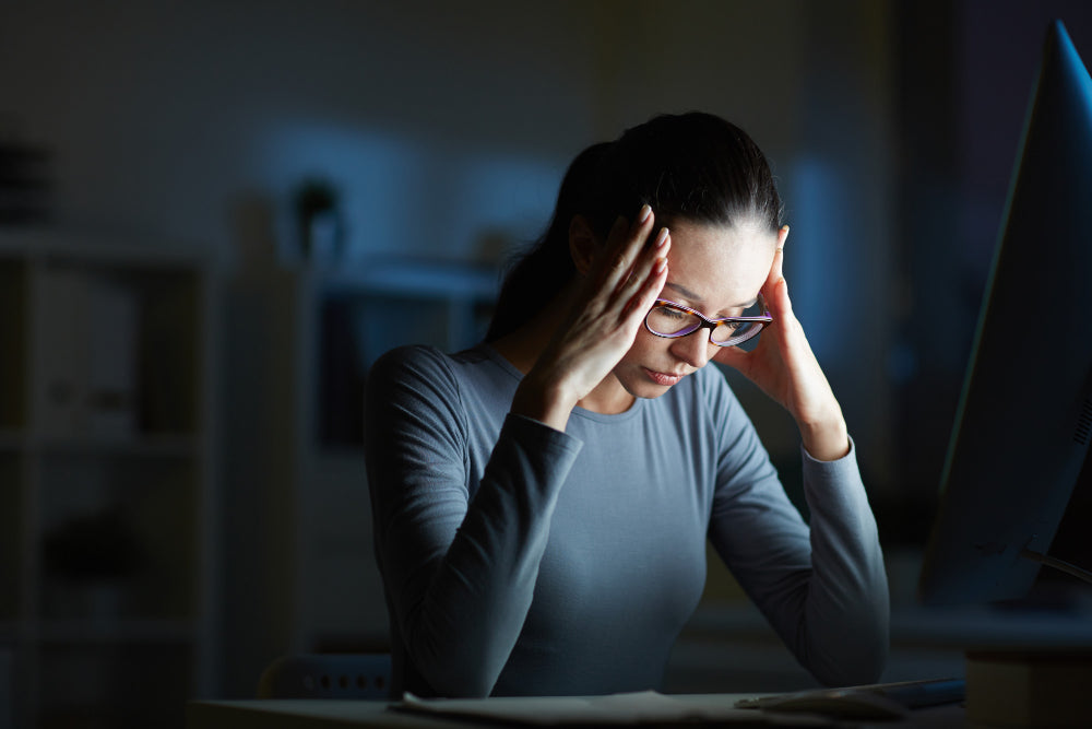 mulher com semblante cansado apoiando as maos sobre as temporas tentando ter mais foco e concentração