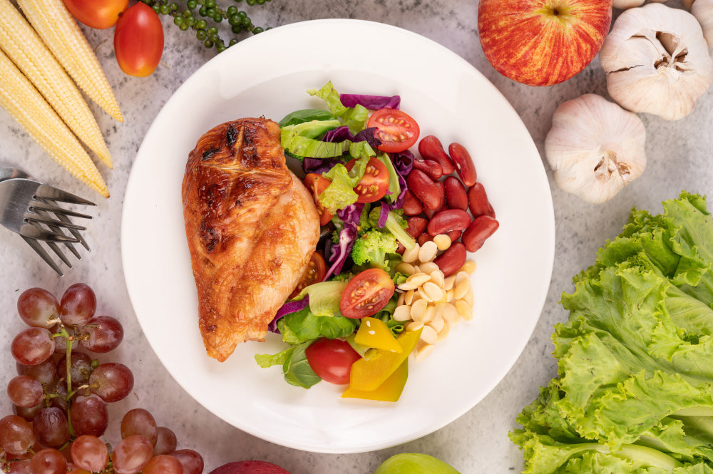 alimentos saudáveis- bife-de-frango-coberto-com-gergelim-branco-ervilhas-tomates-brocolis-e-abobora-em-um-prato-branco