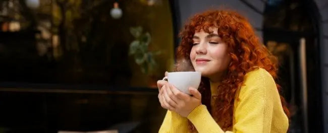 Mulher branca e ruiva tomando chocolate quente saudável
