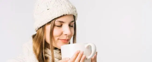 Mulher se cuidando no inverno enquanto toma uma xícara de chá