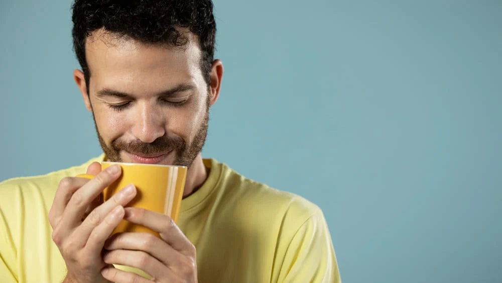 Homem tomando uma caneca de chá de olhos fechados em fundo azul