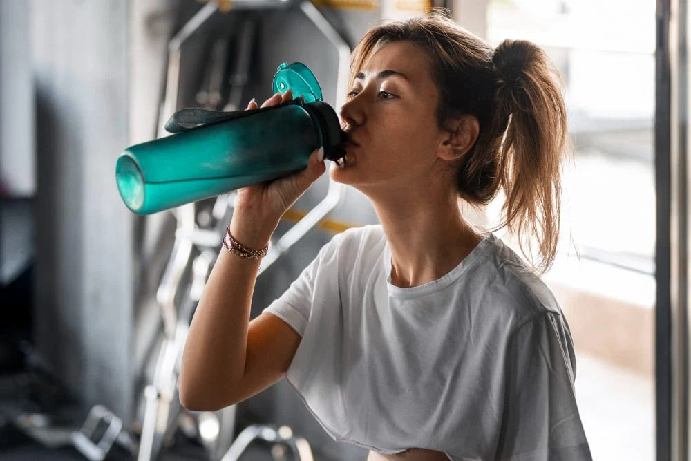 Mulher tomando água em fundo de academia