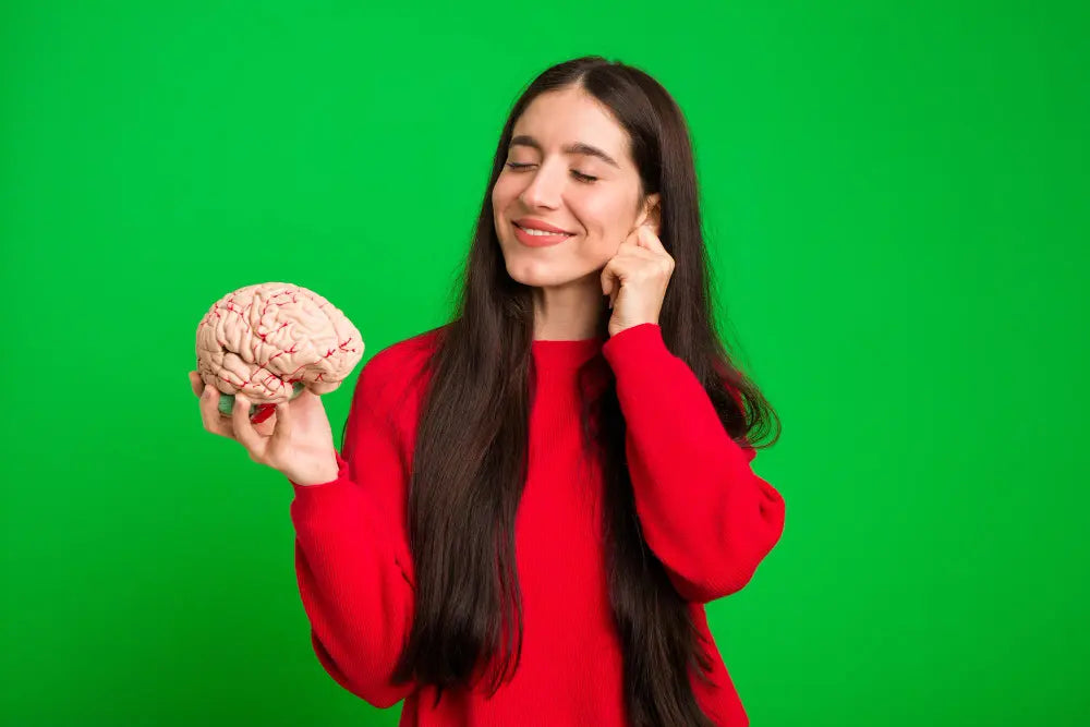 Mulher sorrindo de olhos fechados segurando modelo de cérebro