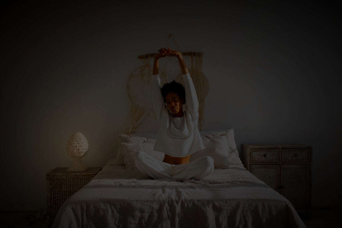 Mulher se alongando na cama antes de dormir – blog Desinchá