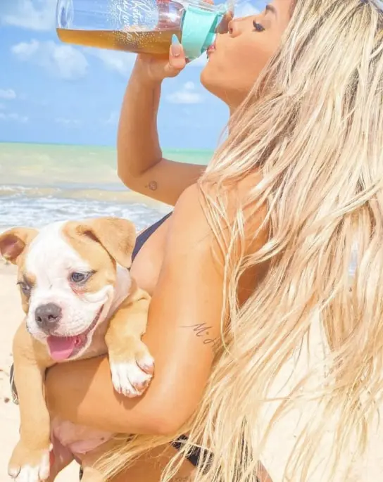 Mulher na praia tomando Desinchá Dia como um drink gelado