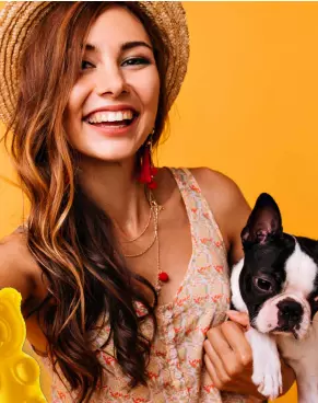 Mulher sorrindo com o cãozinho no colo com fundo laranja