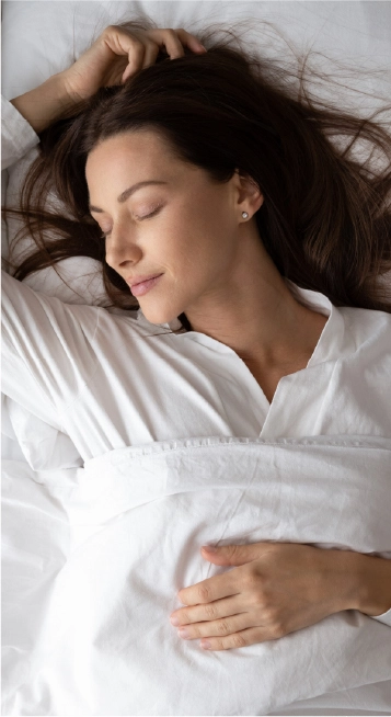 Mulher de pijama branco dormindo embaixo de um cobertor