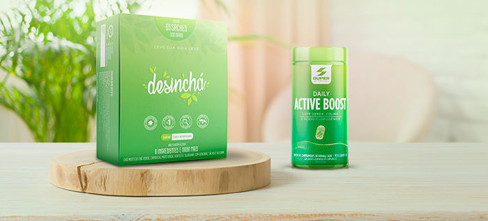 Caixa com 60 sachês de Desinchá ao lado de uma xícara com o chá quentinho e uma embalagem de Daily Active Boost