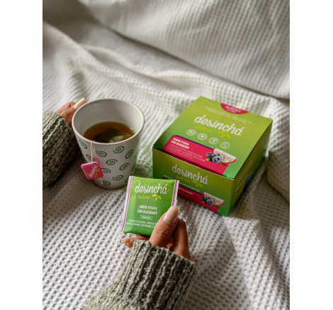 Embalagem do chá de pitaya com blueberry da Desinchá ao lado de uma xícara da bebida